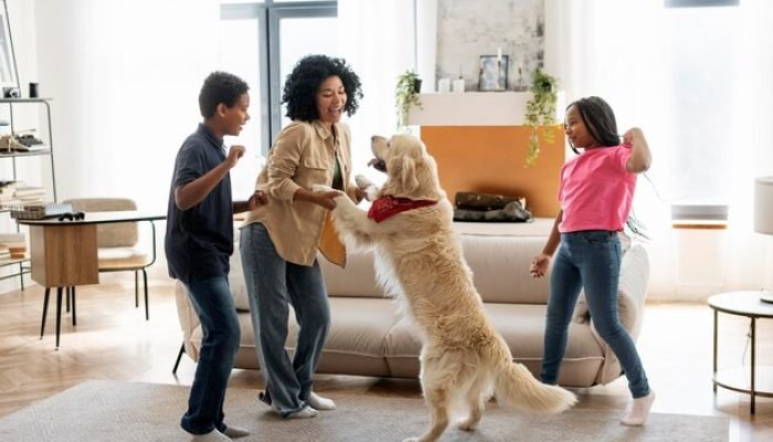 smiling-african-american-family-mother-daughter-son-dancing-with-golden-retriever-home_695242-5276